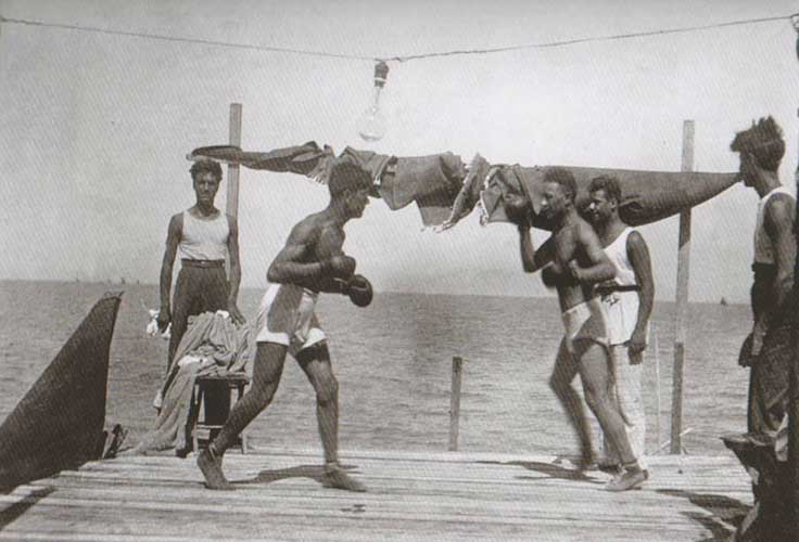Fig. 6. La piattaforma di uno chalet diventa il ring per un incontro di box sulla spiaggia, sopra una lampadina, anni ’20-40, in Perfetti, Carlorosi, Buschi 2007, 180.